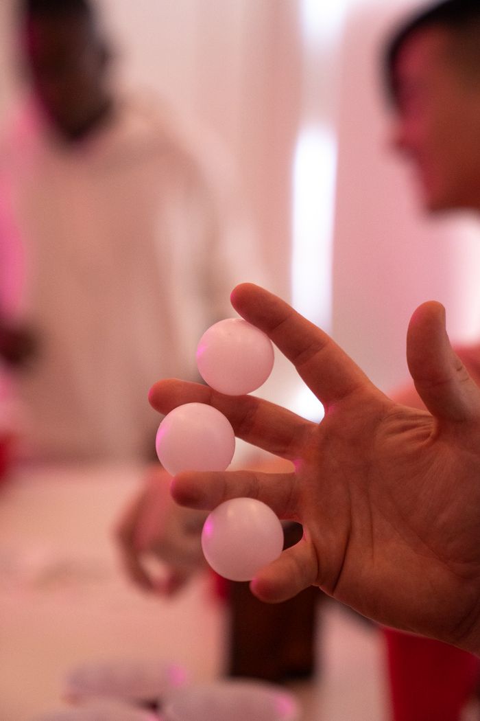 services-01 Selective focus on a hand holding ping pong balls with blurred background of people socializing.